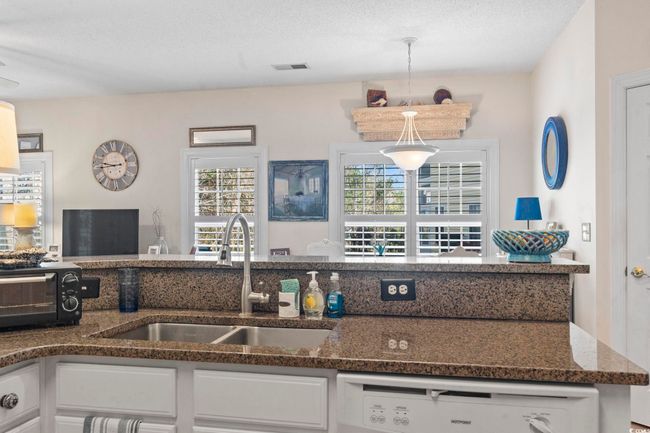 Kitchen featuring a sink, white cabinetry, a wealth of natural light, and white dishwasher | Image 11