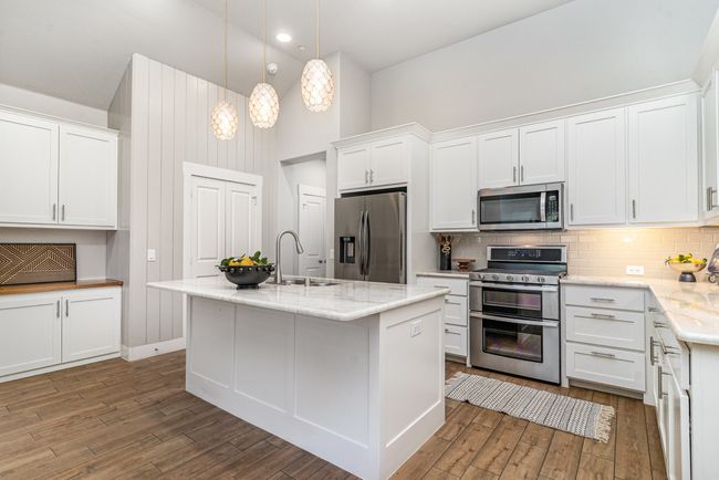 Kitchen featuring appliances with stainless steel finishes, high vaulted ceiling, a sink, hardwood / wood-style flooring, and tasteful backsplash | Image 11