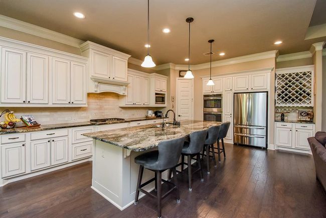 MUST HAVE! This kitchen boasts of granite counter and a large breakfast bar to easily accommodate 4 bar stools with pendants lights above! | Image 17