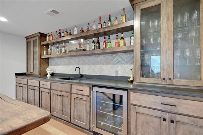 Bar featuring a sink, decorative backsplash, wet bar, wine cooler, and visible vents | Image 47