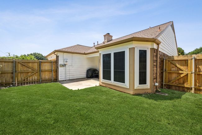 Back of house with a gate, a patio area, a shingled roof, and a chimney | Image 25