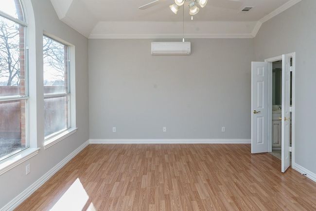 Spare room with baseboards, visible vents, vaulted ceiling, light wood-style floors, and a wall mounted AC | Image 11