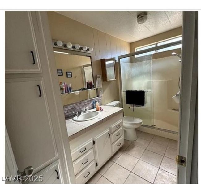 Bathroom featuring tasteful backsplash, vanity, a stall shower, tile patterned floors, and toilet | Image 6