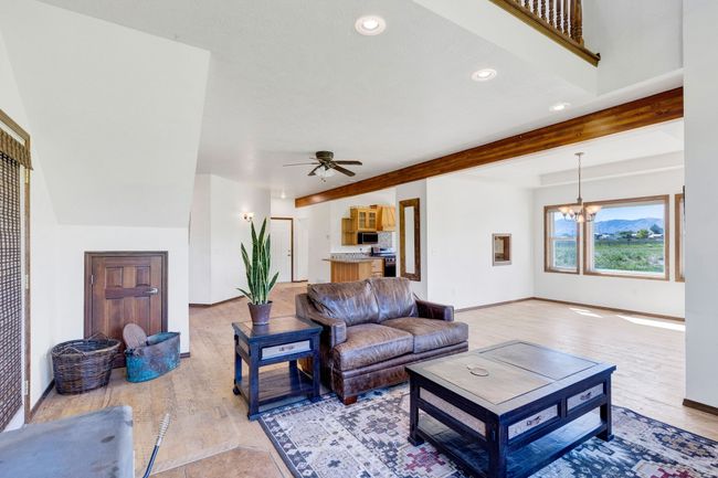 Living area with light wood-style floors, a chandelier, ceiling fan, recessed lighting, and beamed ceiling | Image 17