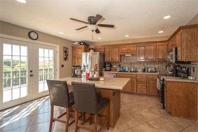 Kitchen featuring sink, french doors, stainless steel appliances, a center island, and decorative backsplash | Image 2