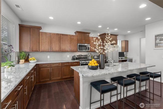 Step into this beautifully designed chef’s kitchen, where style meets functionality. Featuring rich wood cabinetry, sleek stainless steel appliances, and gleaming granite countertops! | Image 9