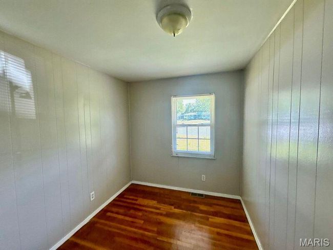 Unfurnished room with dark wood-type flooring, wood walls, and baseboards | Image 4