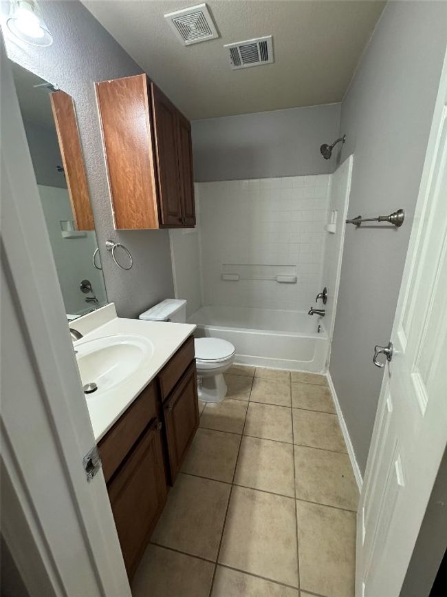 Full bathroom featuring toilet, tile patterned flooring, vanity, shower / washtub combination, and baseboards | Image 20