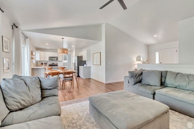 Living room featuring light wood-style flooring, ceiling fan, lofted ceiling, recessed lighting, and plenty of natural light | Image 6