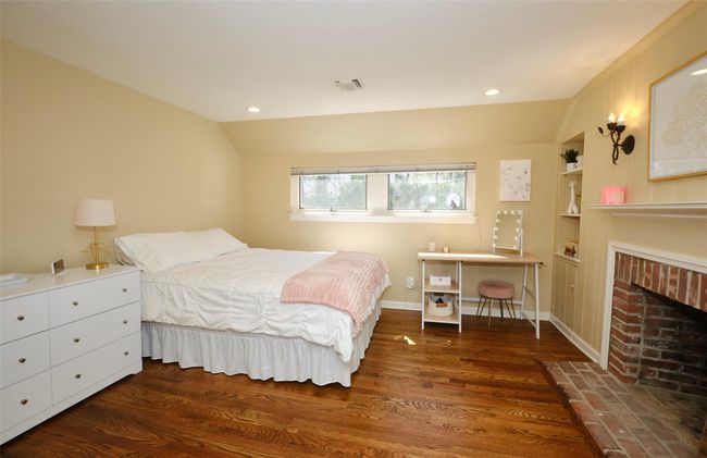 Bedroom featuring vaulted ceiling, recessed lighting, visible vents, a fireplace, and wood finished floors | Image 16