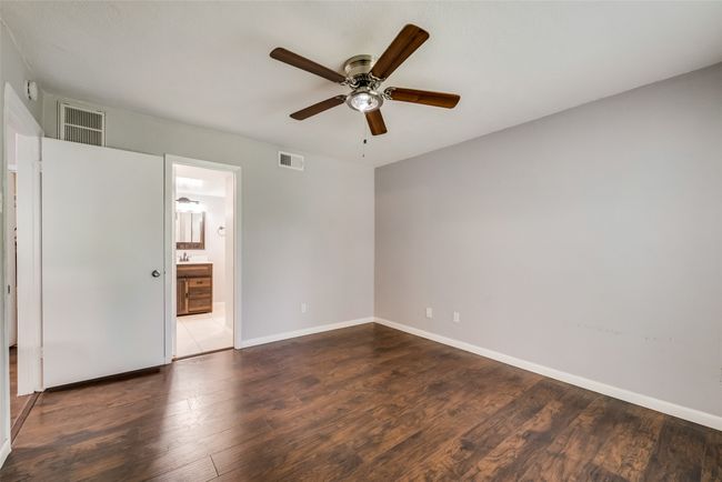 Unfurnished bedroom featuring dark wood-type flooring, a ceiling fan, and ensuite bath | Image 9