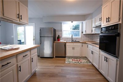 Kitchen with white cabinets, stainless steel appliances, and light hardwood / wood-style flooring | Image 1