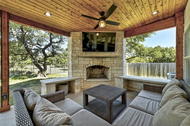 Fenced backyard with an outdoor living space with a fireplace, a patio, and a ceiling fan | Image 27