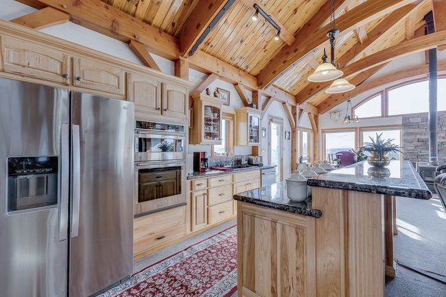 Kitchen featuring lofted ceiling with beams, stainless steel appliances, wood ceiling, light brown cabinetry, and glass insert cabinets | Image 6