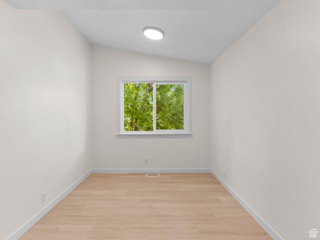 Empty room featuring light wood-style floors and lofted ceiling | Image 13