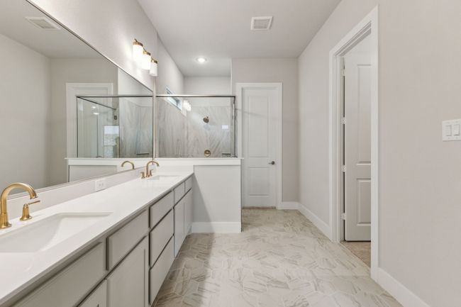 Bathroom featuring a marble finish shower, double vanity, and marble look tiles | Image 19