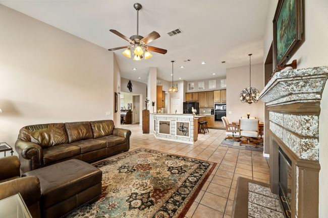 Living room with light tile patterned floors, a chandelier, ceiling fan, recessed lighting, and a fireplace with flush hearth | Image 14