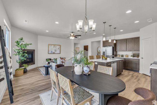 Dining area with ceiling fan with notable chandelier, light hardwood / wood-style floors, and sink | Image 15