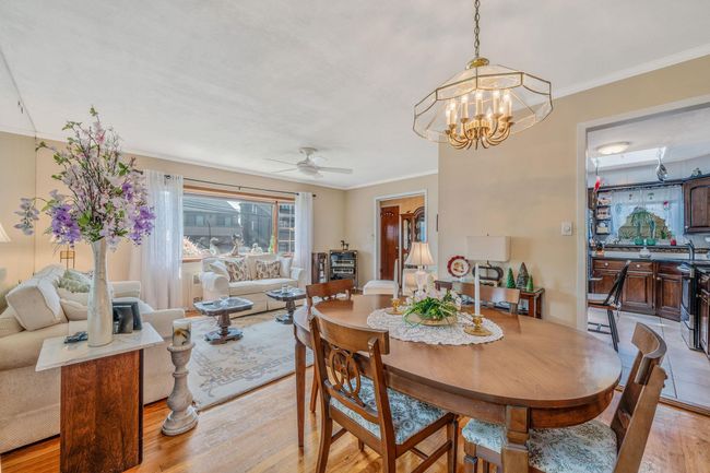 Dining area featuring light wood-style flooring, ornamental molding, a ceiling fan, and a chandelier | Image 8