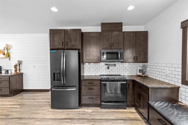 Kitchen with dark brown cabinets, stainless steel appliances, and light wood-style floors | Image 8