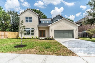 This is a modern two-story home featuring a brick facade, a two-car garage, and large windows. The property includes a freshly landscaped lawn and a wooden privacy fence on both sides. | Image 3