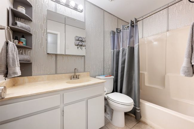 Bathroom featuring shower / bath combination with curtain, toilet, vanity, and tile patterned floors | Image 21