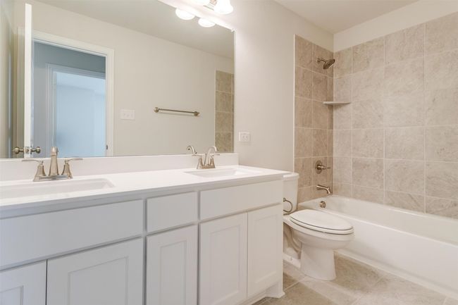 Full bathroom featuring tiled shower / bath, vanity, toilet, and tile patterned floors | Image 30
