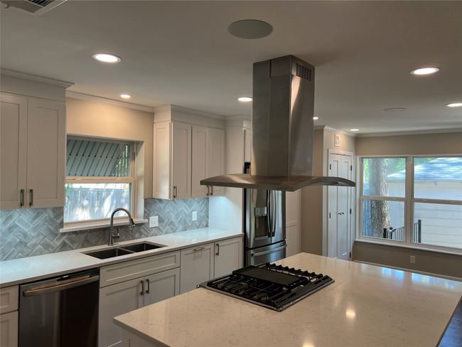 Kitchen with island range hood, decorative backsplash, appliances with stainless steel finishes, light stone counters, and plenty of natural light | Image 11