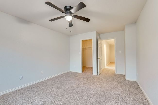 Unfurnished bedroom featuring light colored carpet, a walk in closet, a closet, and a ceiling fan | Image 30