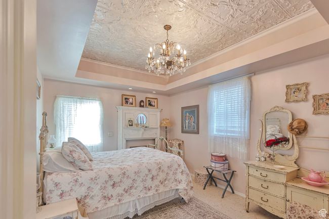 Carpeted bedroom with a raised ceiling, a notable chandelier, and crown molding | Image 24
