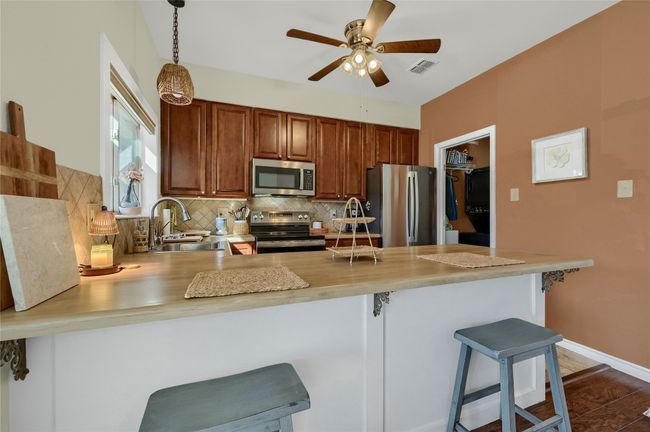 Kitchen with stainless steel appliances, a sink, a peninsula, and light countertops | Image 8