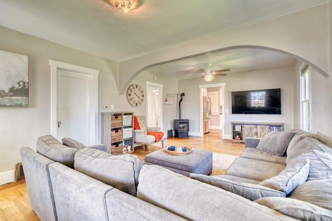 Living room featuring arched walkways, a wood stove, light wood-style floors, and ceiling fan | Image 14