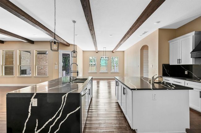 Kitchen featuring dark wood-style flooring, dark countertops, a sink, and a center island with sink | Image 39
