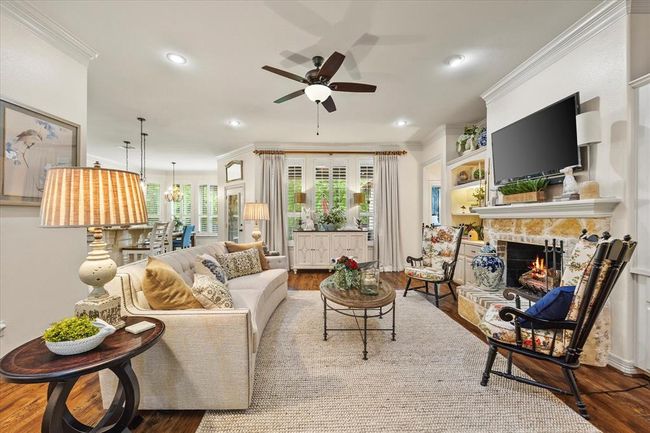 Living room featuring wood-type flooring, ceiling fan, crown molding, and a stone fireplace | Image 15