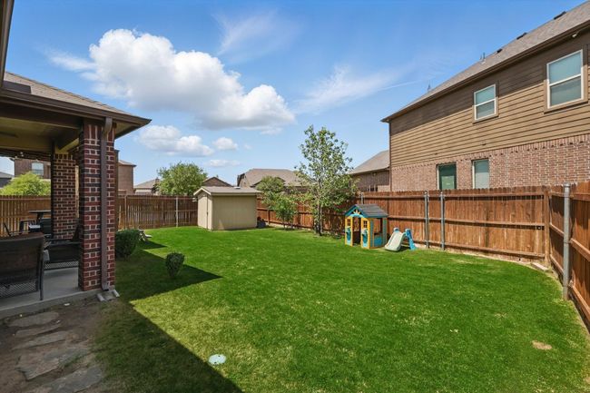 View of yard featuring an outdoor structure, a shed, a patio area, a fenced backyard, and a playground | Image 37