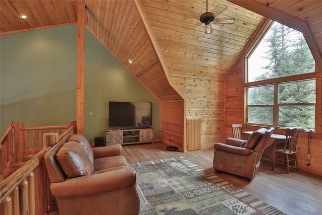 Living room featuring wooden ceiling, wood walls, wood-type flooring, and high vaulted ceiling | Image 39