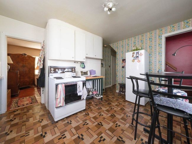 Kitchen featuring white appliances, wallpapered walls, and white cabinets | Image 12