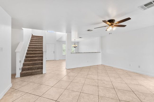 Unfurnished living , light tile patterned floors, ceiling fan, stairs, and baseboards | Image 17