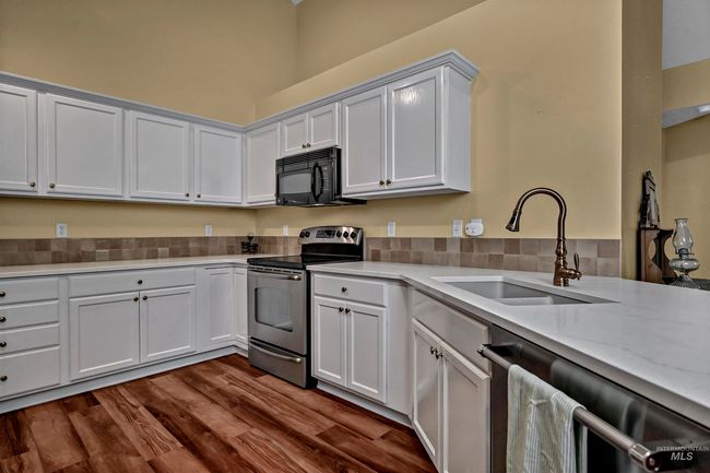 Kitchen with appliances with stainless steel finishes, light countertops, dark wood-type flooring, and white cabinetry | Image 13
