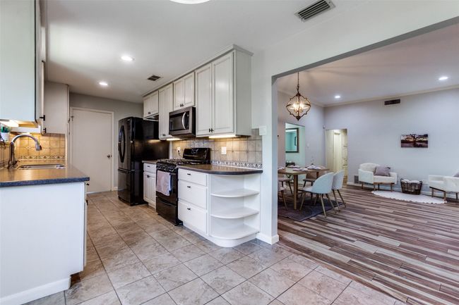 Kitchen featuring black appliances, dark countertops, open shelves, tasteful backsplash, and recessed lighting | Image 6