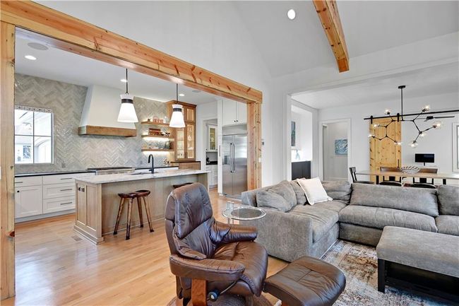 Living area with lofted ceiling with beams, a chandelier, light wood finished floors, and recessed lighting | Image 14