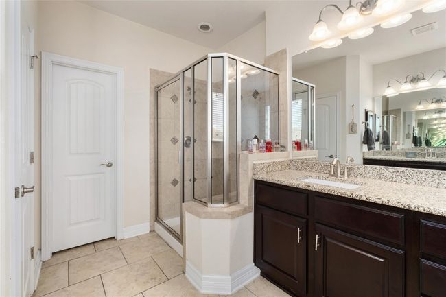 Bathroom featuring visible vents, a stall shower, tile patterned flooring, and vanity | Image 17