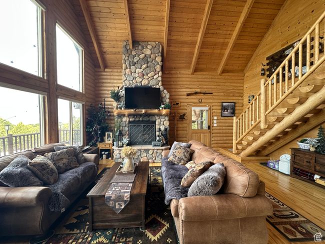 Living area featuring rustic walls, beamed ceiling, high vaulted ceiling, wooden ceiling, and wood finished floors | Image 6