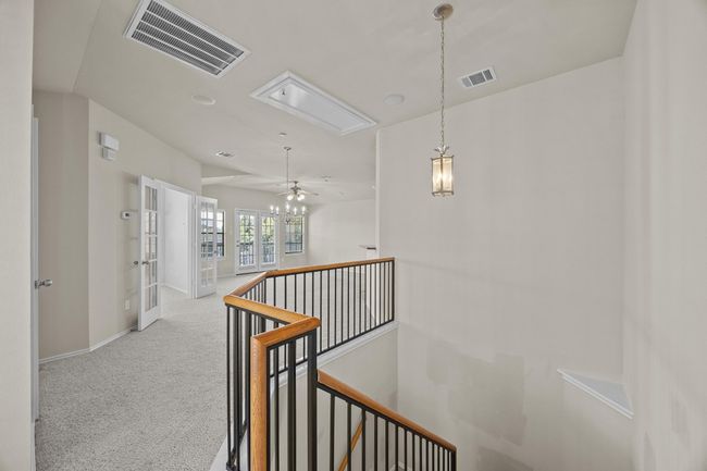 Hallway featuring carpet floors, an upstairs landing, visible vents, and attic access | Image 5