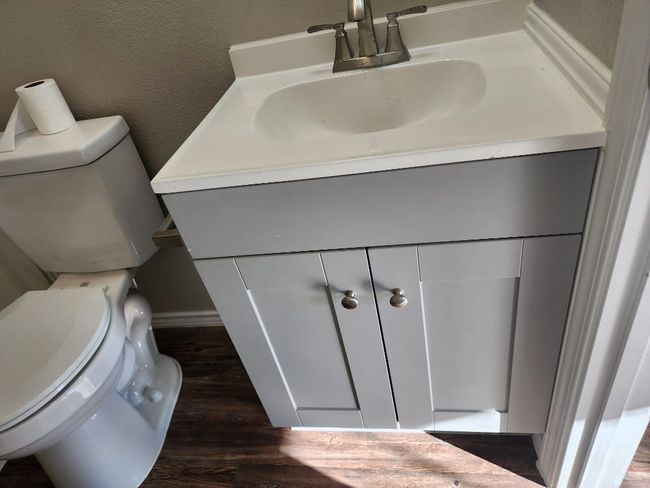 Half bath featuring toilet, vanity, a textured wall, and wood finished floors | Image 11