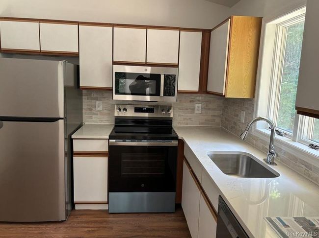 Kitchen with appliances with stainless steel finishes, light countertops, white cabinetry, and backsplash | Image 5