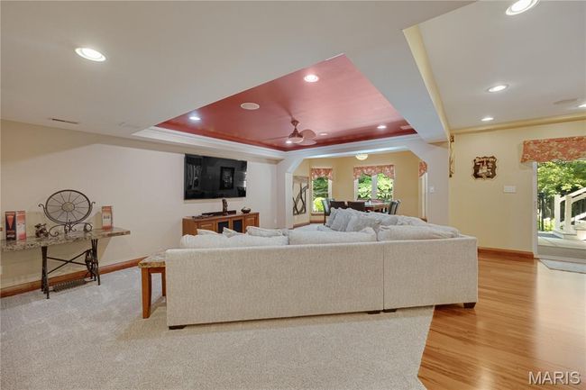 Living room with arched walkways, plenty of natural light, recessed lighting, light wood-type flooring, and a tray ceiling | Image 46