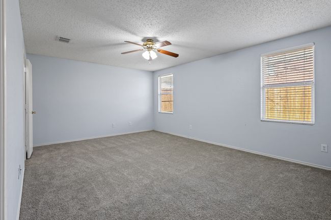 Carpeted empty room with a textured ceiling and ceiling fan | Image 11