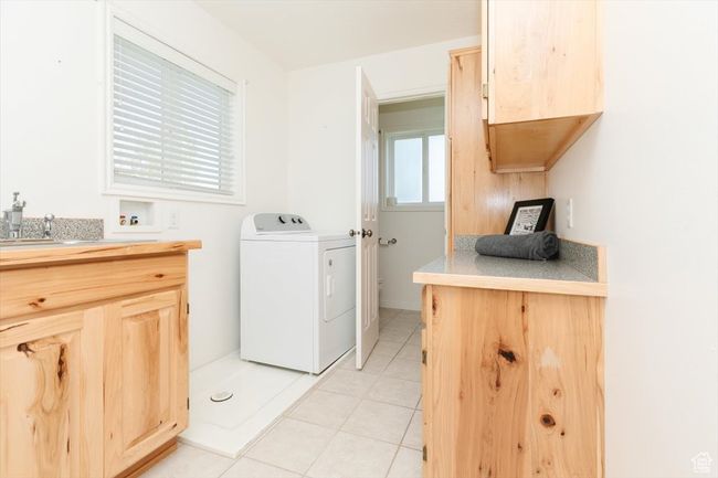 Laundry area with washer / clothes dryer, light tile patterned flooring, and cabinet space | Image 42