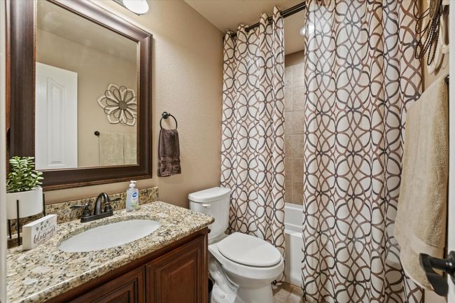 Bathroom featuring a textured wall, shower / bath combo with shower curtain, vanity, and toilet | Image 29